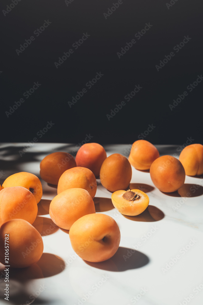 Wall mural food composition with fresh apricots on light marble surface with black background