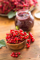 Fresh red currants in bowl and jam marmalade on wooden table