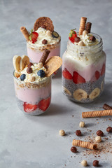 Chia pudding with yoghurt, honey, strawberry and banana on pastel concrete background