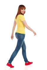 Young Casual Woman Is Walking And Looking At Camera Over The Shoulder