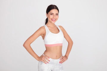portrait of confident fit girl in white gym outfit standing