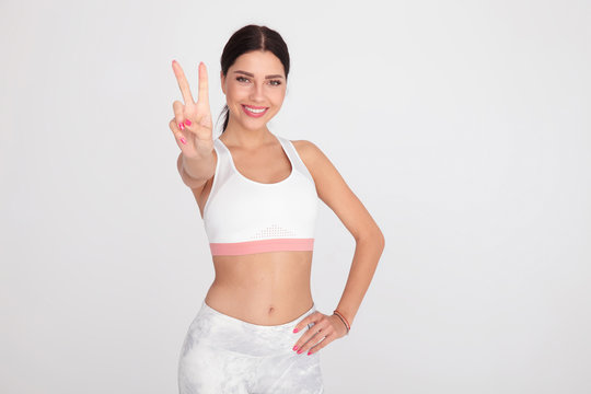 beautiful fitness woman makes peace sign while standing
