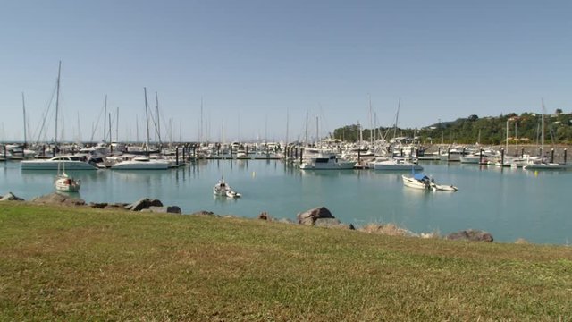 A pan to right shot of a pier where white yachts are docked.