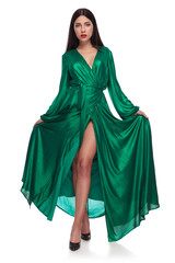 elegant woman holding her long green dress while standing cross-legged