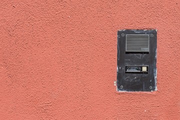 Abgenutzte Haustürklingel mit Gegensprechanlage an einer Hauswand 
