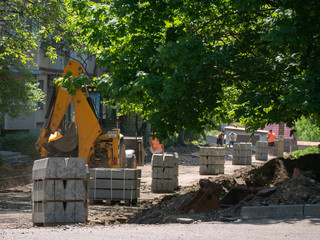 Excavator Making and constructing a new asphalt road near the civil building. Concepts of improvement of the territory of buildings. Housing and utilities concepts