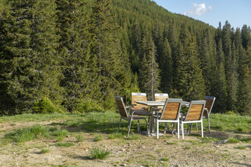 Relaxing place near forest, wooden table and chairs, in Bucegi Mountains, Bucegi National Park, Romania