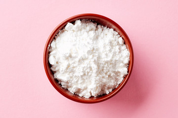 Bowl of powder sugar on white background, from above