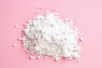 Heap of powder sugar on pink, from above