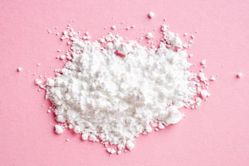 Heap of powder sugar on pink, from above