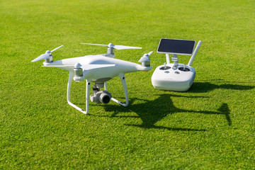 White drone camera and controller in front of green grass