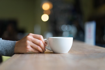 Girl holding a mug with bokeh lights in the background