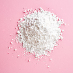 Heap of powder sugar on pink, from above