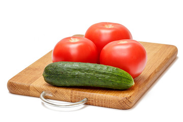 Tomatoes and cucumber on wooden cutting board