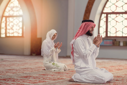 Muslim man and woman praying for Allah in the mosque together