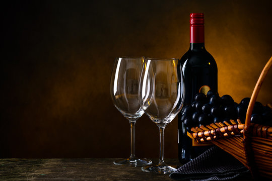 Still life with bottle of red wine, two wineglasses and grape in