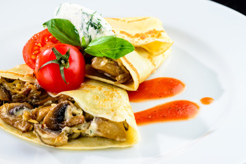 Homemade tasty pancakes blinis served with mushrooms and tomat