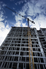 Fototapeta na wymiar High-rise building under construction. The site with crane against blue sky