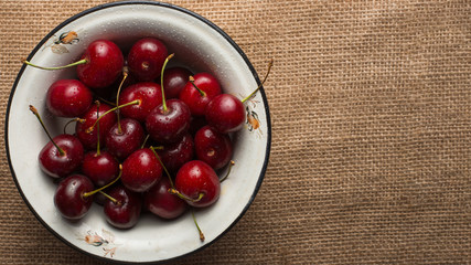 Sweet cherries in a bowl, a fabric background, with an empty space for the inscription