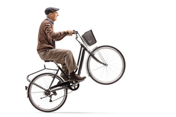 Mature man riding a bicycle and doing a wheelie