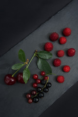 Fruit of currant, cherry and raspberries on black background