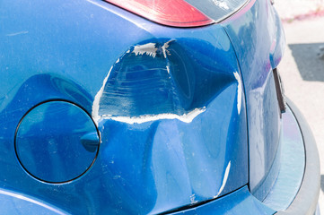 Blue scratched car with damaged paint in crash accident or parking lot and dented damage of metal...