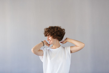 Сoncept dizzying success. Young wonderful girl keeps herself for curly head, rejoices in her...