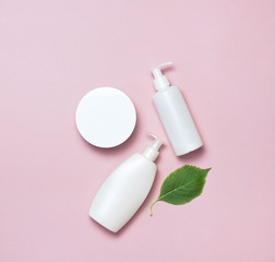 Cosmetic bottle containers with hydrangea flower on a pink minimalistic background flat lay. Blank label for branding mock-up. Natural beauty product concept.