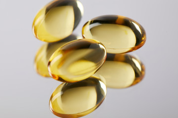 heap of omega fish hat supplement capsules on reflective surface