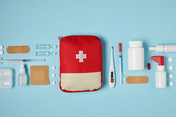 top view of red first aid kit bag on blue surface with medical supplies