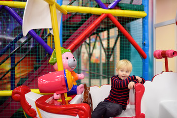 Fototapeta na wymiar Happy little boy having fun in amusement in play center