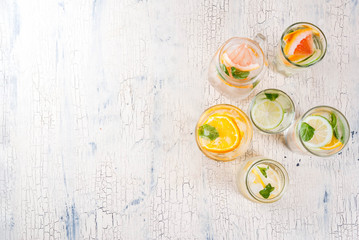 Summer healthy cocktails, set of various citrus infused waters, lemonades or mojitos, with lime lemon orange grapefruit, diet detox beverages, in different glasses light background copy space