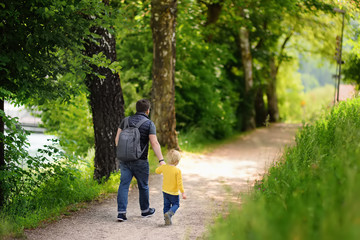 Cheerful little boy and his father enjoying warm summer day