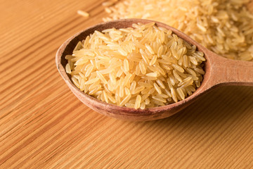 Old wooden spoon with rice on a wooden table. Close up. The concept of natural food