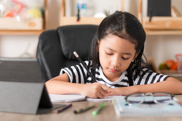 Asian little girl doing homework on wooden table select focus shallow depth of field