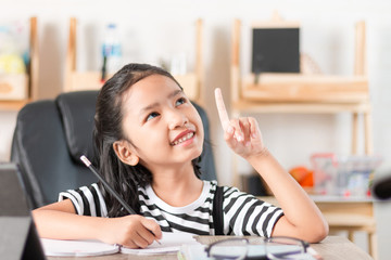 Asian little girl doing homework on wooden table select focus shallow depth of field