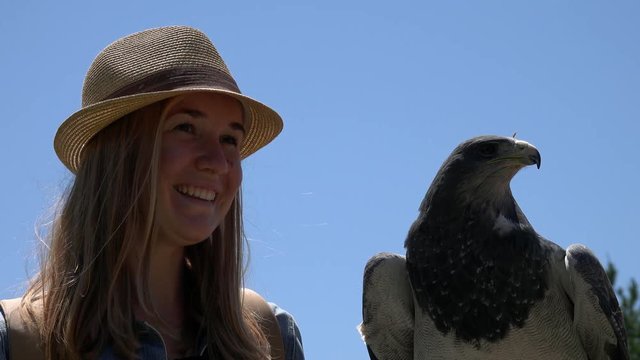 Female Tourist Posing for Photo with Black-Chested Buzzard-Eagle (Geranoaetus melanoleucus)