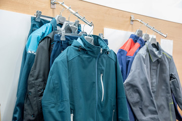 The upper work clothes of strong fabric of different colors with pockets hang on the hangers as a...
