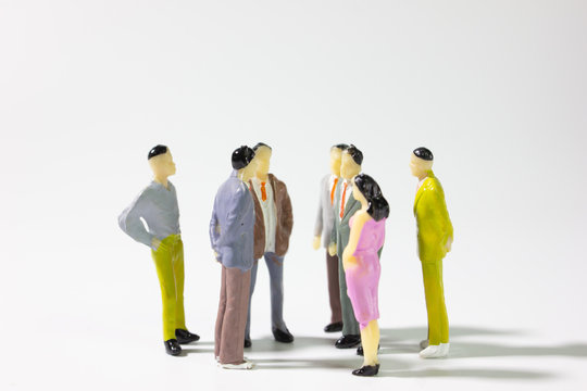 A group of miniature businessman  stand meeting on white background side view closeup.