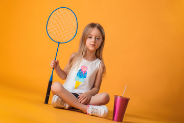 Little girl posing with a tennis racket and a shaker in the studio