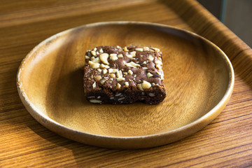 Brownie cake or chocolate brownie almond cake in wood plate on a wood tray background