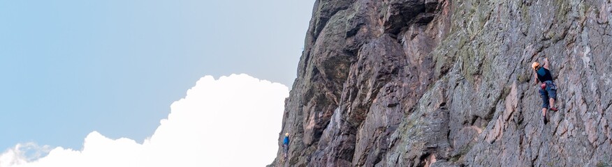 Rock climbing. A group of young rock climbers climb the vertical granite rock. Extreme sport. Training of mountaineers.