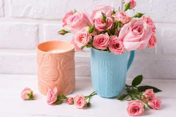 Pink roses flowers in blue cup  and burning candle