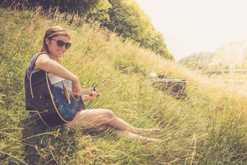Junges Mädchen sitzt in der Wiese und spielt Gitarre, Lächeln