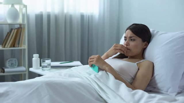 Sad and frustrated woman taking strong pills lying in bed, chemotherapy course