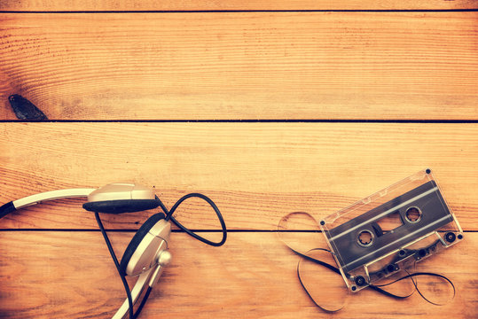 Headphones and translucent audio cassette tape on vintage wood planks  background white copy space