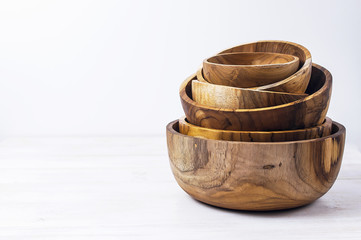 Wooden utensils for the kitchen, bowls, plates on a light background. The concept of natural dishes, a healthy lifestyle. Texture of wood.