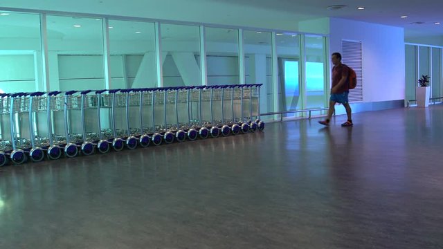 A man takes a baggage cart and puts a backpack