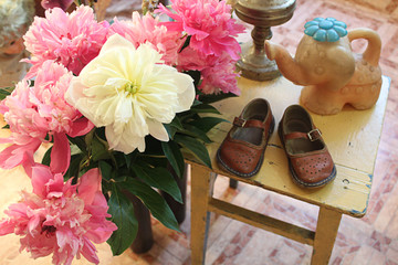 Interior design of the room with beautiful garden flowers and children's shoes