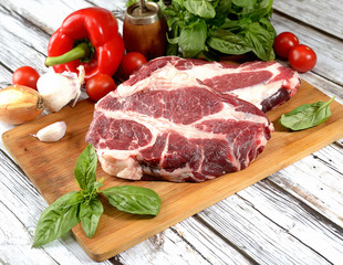 fresh raw meat, herbs and spices on a cutting board on a wooden background